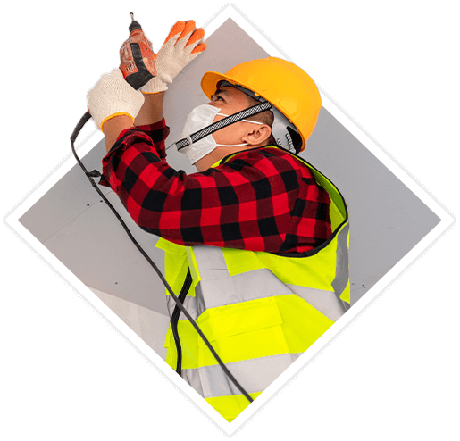 Person wearing safety equipment drilling in drywall